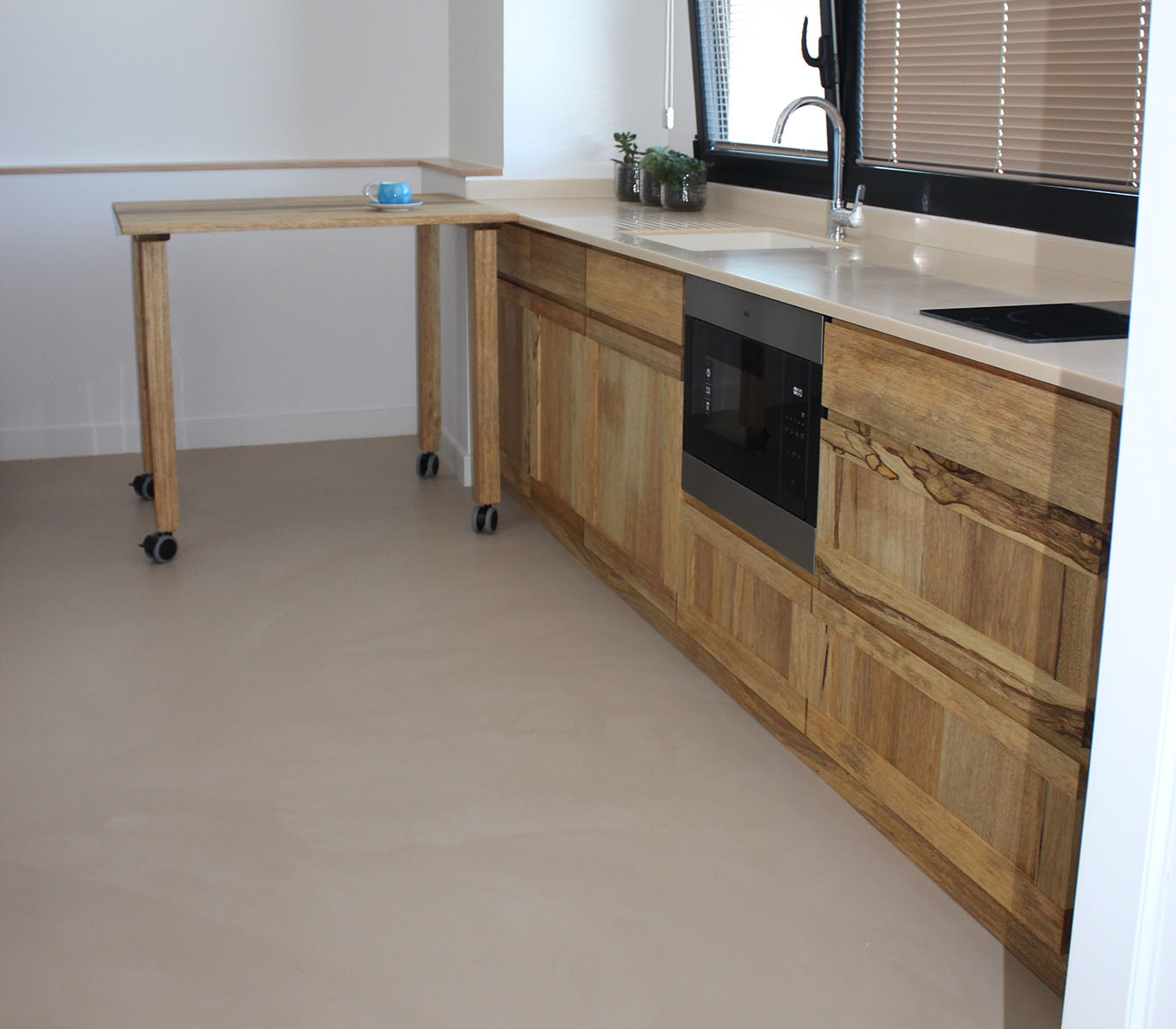 Façades — Fraké.
Finition — Huile Rubio®.
Poignées — Portes profilées.
Plan de travail et évier — Résine Staron®.
Table — Îlot d'appoint mobile.