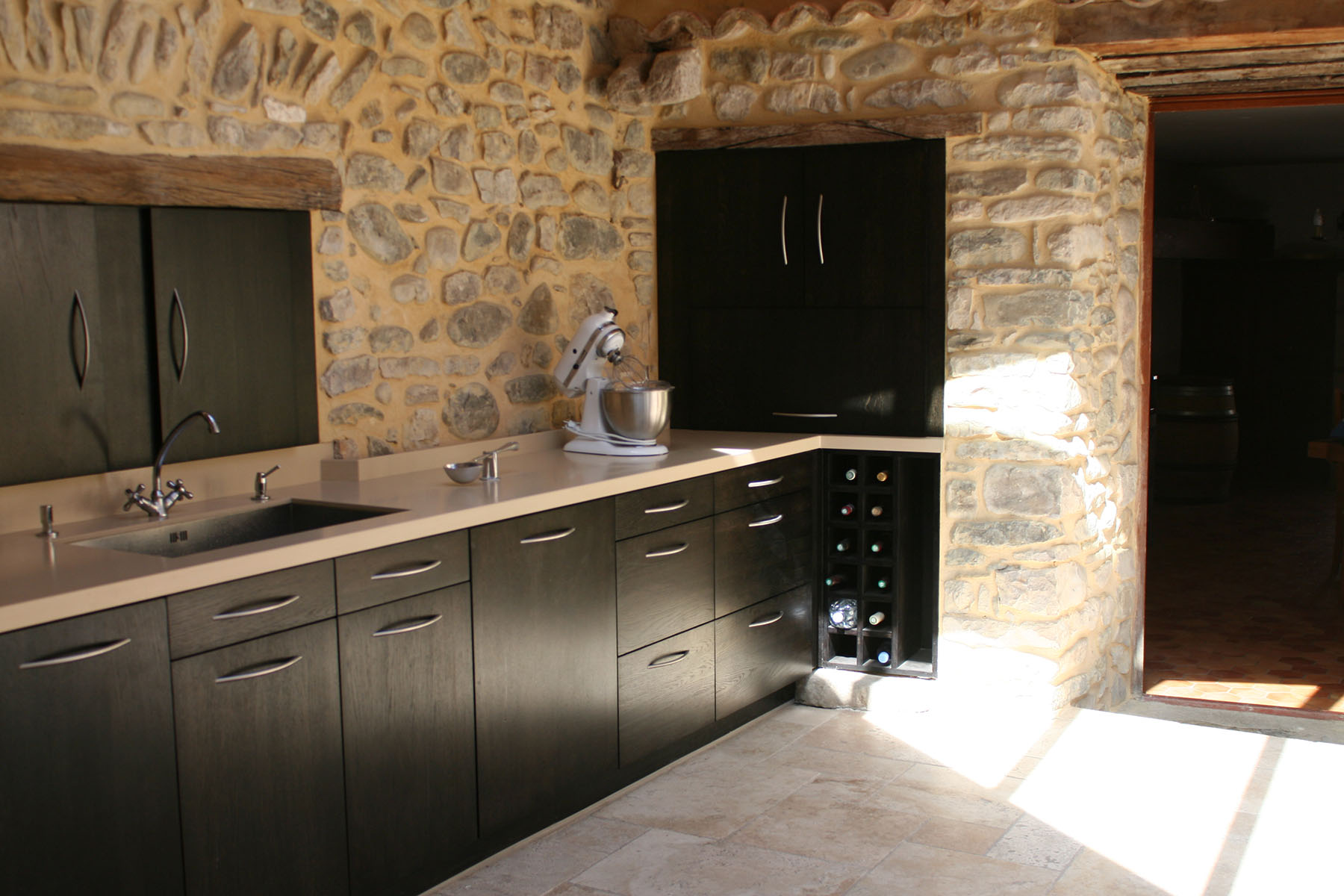 Façades — Chêne massif, teinté noir, verni.
Poignées — Inox brossé.
Plan de travail — Résine.